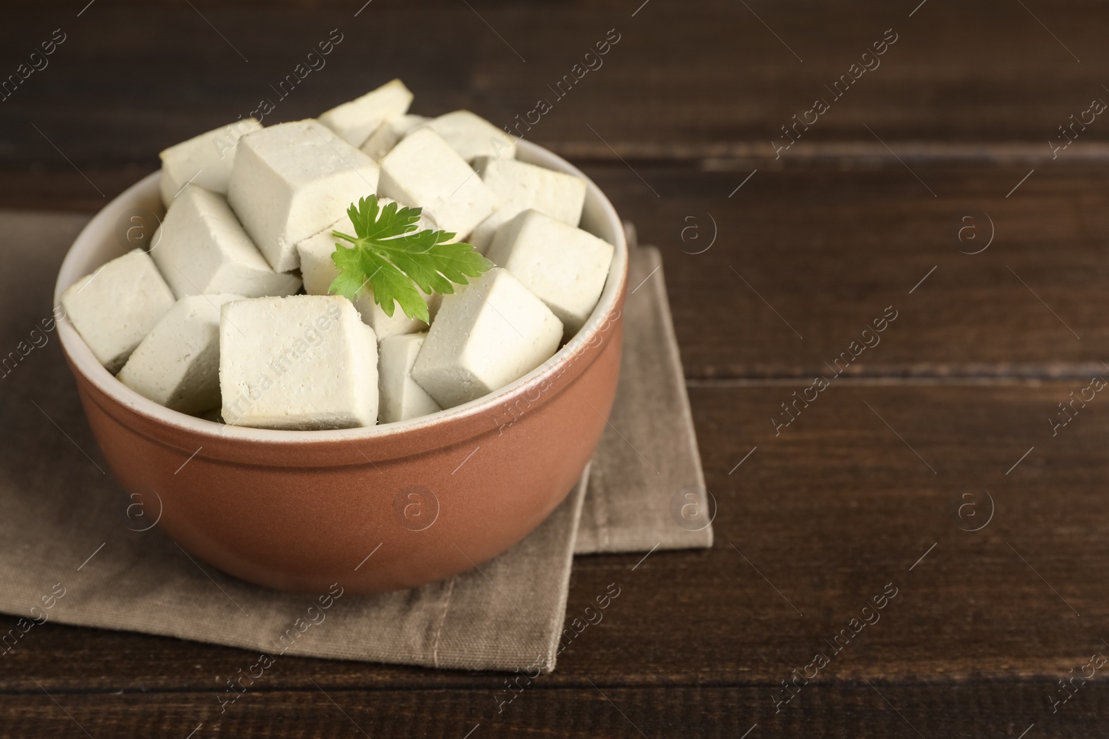 Photo of Delicious tofu with parsley on wooden table. Space for text