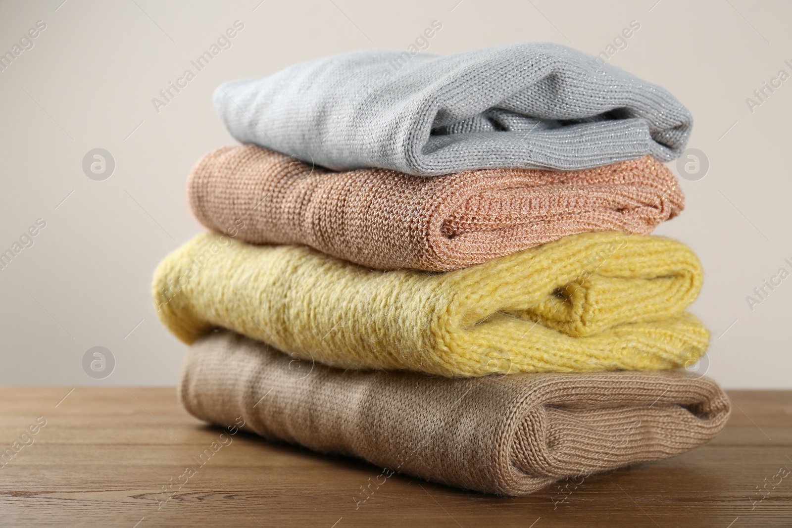 Photo of Stack of knitted sweaters on wooden table