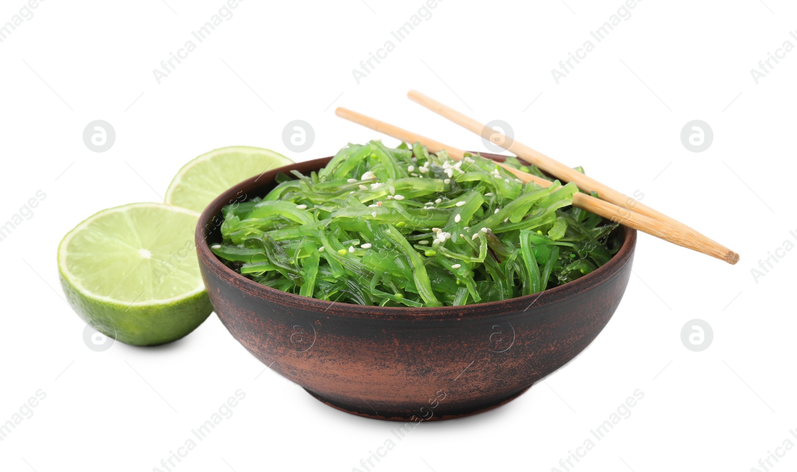 Photo of Tasty seaweed salad in bowl, chopsticks and pieces of lime isolated on white