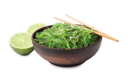 Tasty seaweed salad in bowl, chopsticks and pieces of lime isolated on white