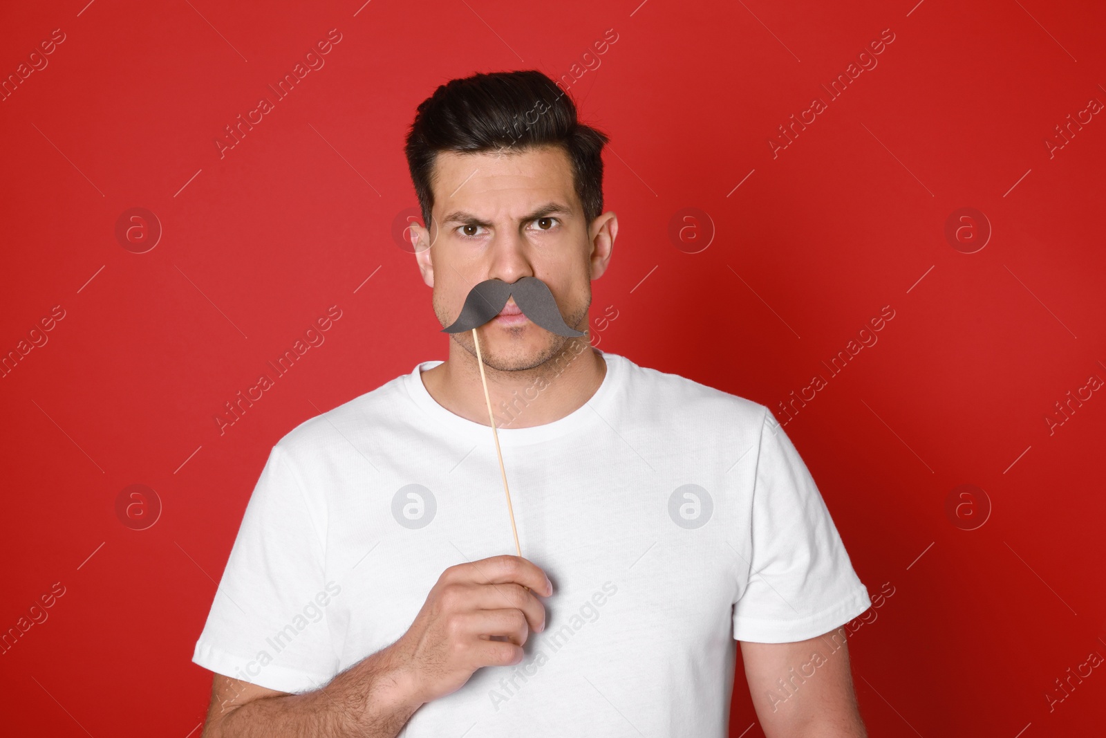 Photo of Funny man with fake mustache on red background