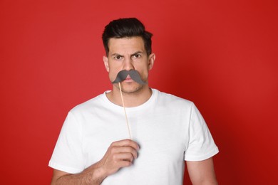 Photo of Funny man with fake mustache on red background