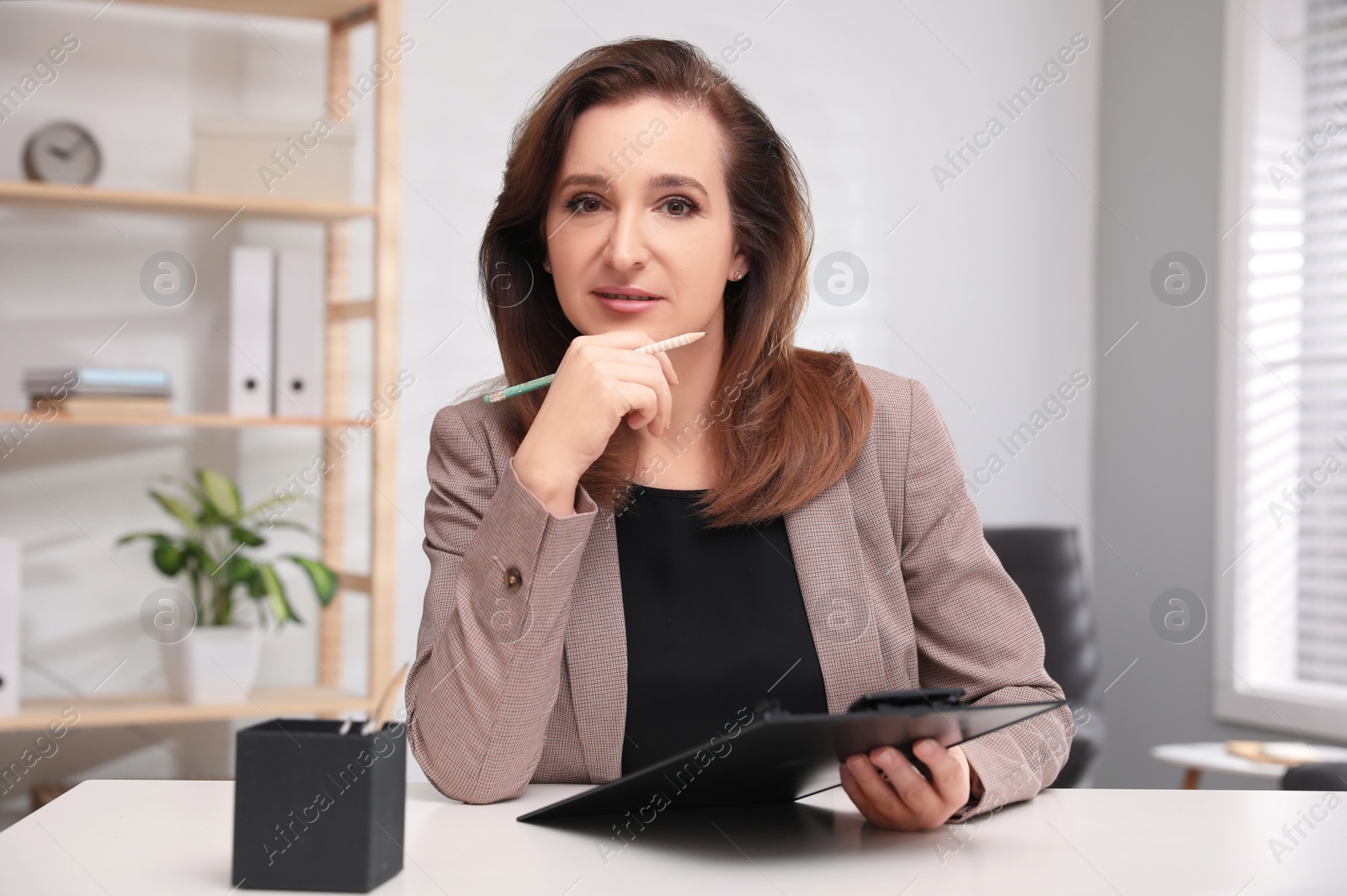 Photo of Portrait of psychotherapist with clipboard at table in office