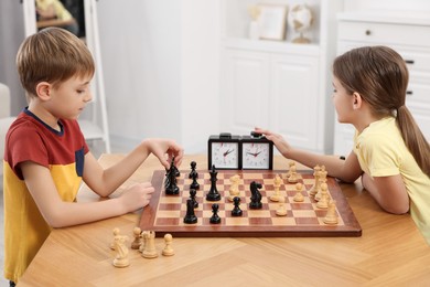 Photo of Cute children playing chess at table in room