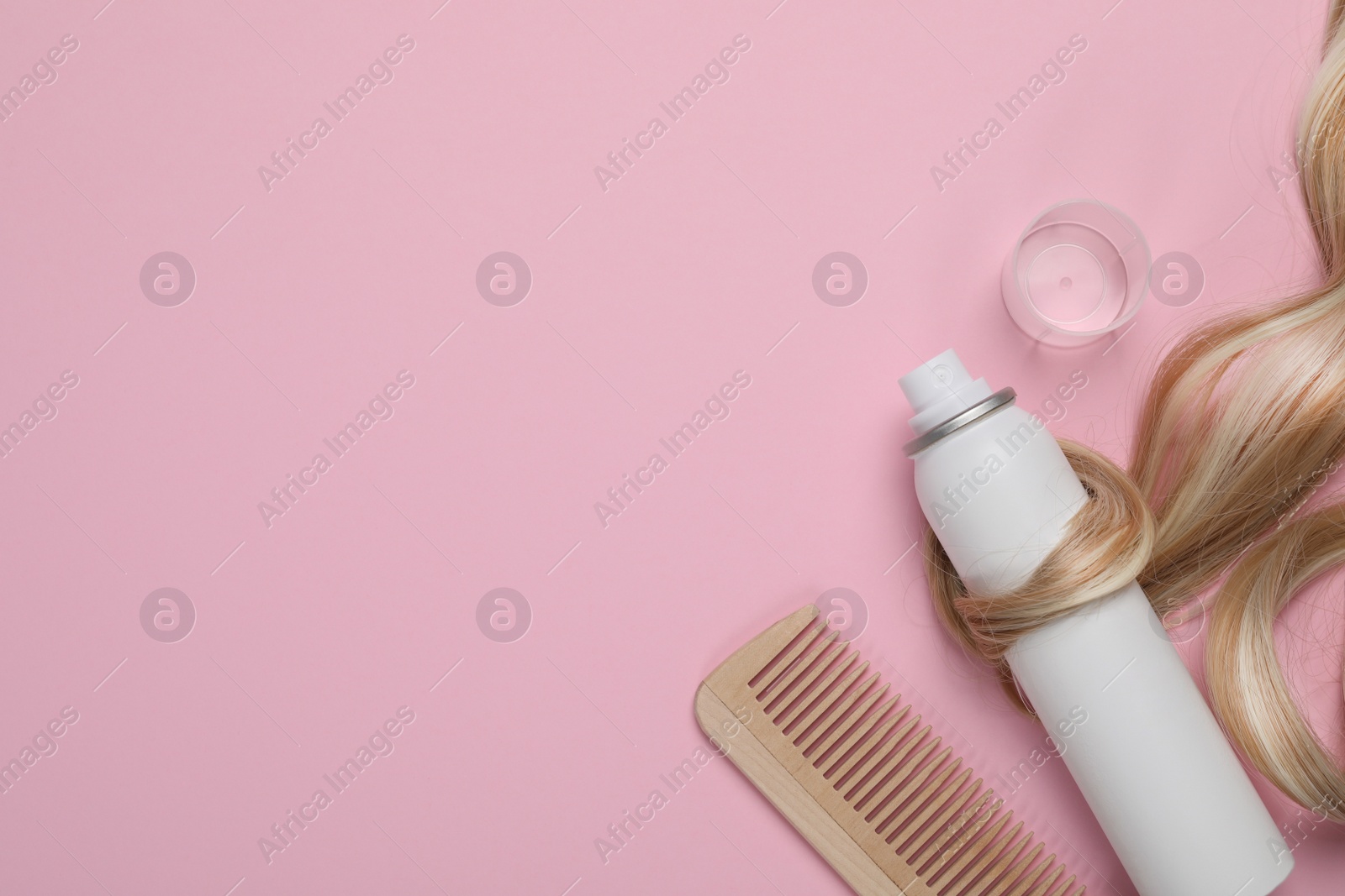 Photo of Lock of healthy blond hair, comb and cosmetic product on pink background, flat lay. Space for text