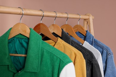 Photo of Rack with stylish clothes on wooden hangers against beige background, closeup