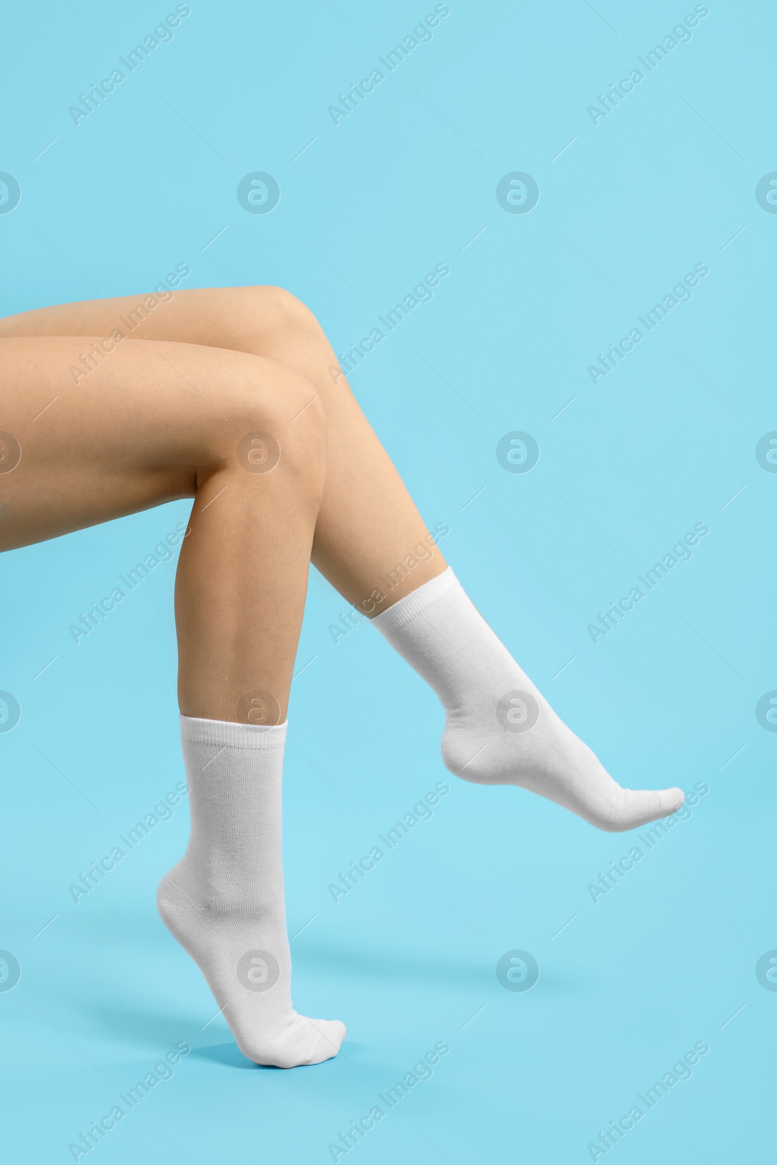 Photo of Woman in stylish white socks on light blue background, closeup