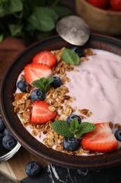 Photo of Bowl with yogurt, berries and granola on table, closeup