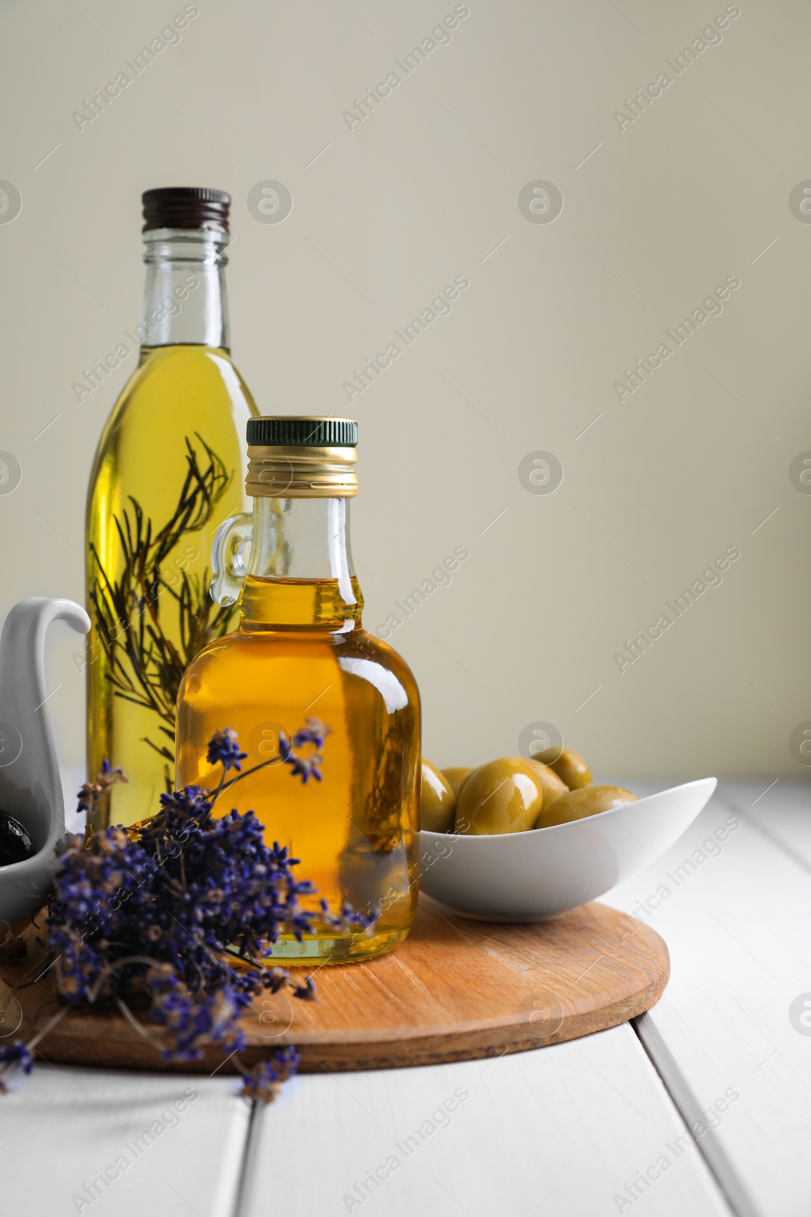 Photo of Different cooking oils and ingredients on white wooden table against light background