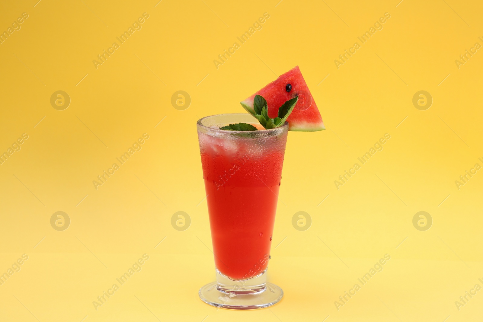 Photo of Delicious drink with mint, piece of fresh watermelon and ice cubes on yellow background