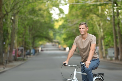Photo of Handsome man riding bicycle outdoors on summer day