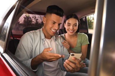 Happy couple with smartphone in modern taxi