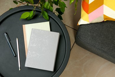 Photo of Books, pen and pencil on black table near sofa indoors, top view