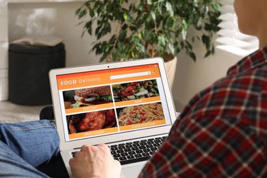 Photo of Man using laptop for ordering food online at home, closeup. Delivery service