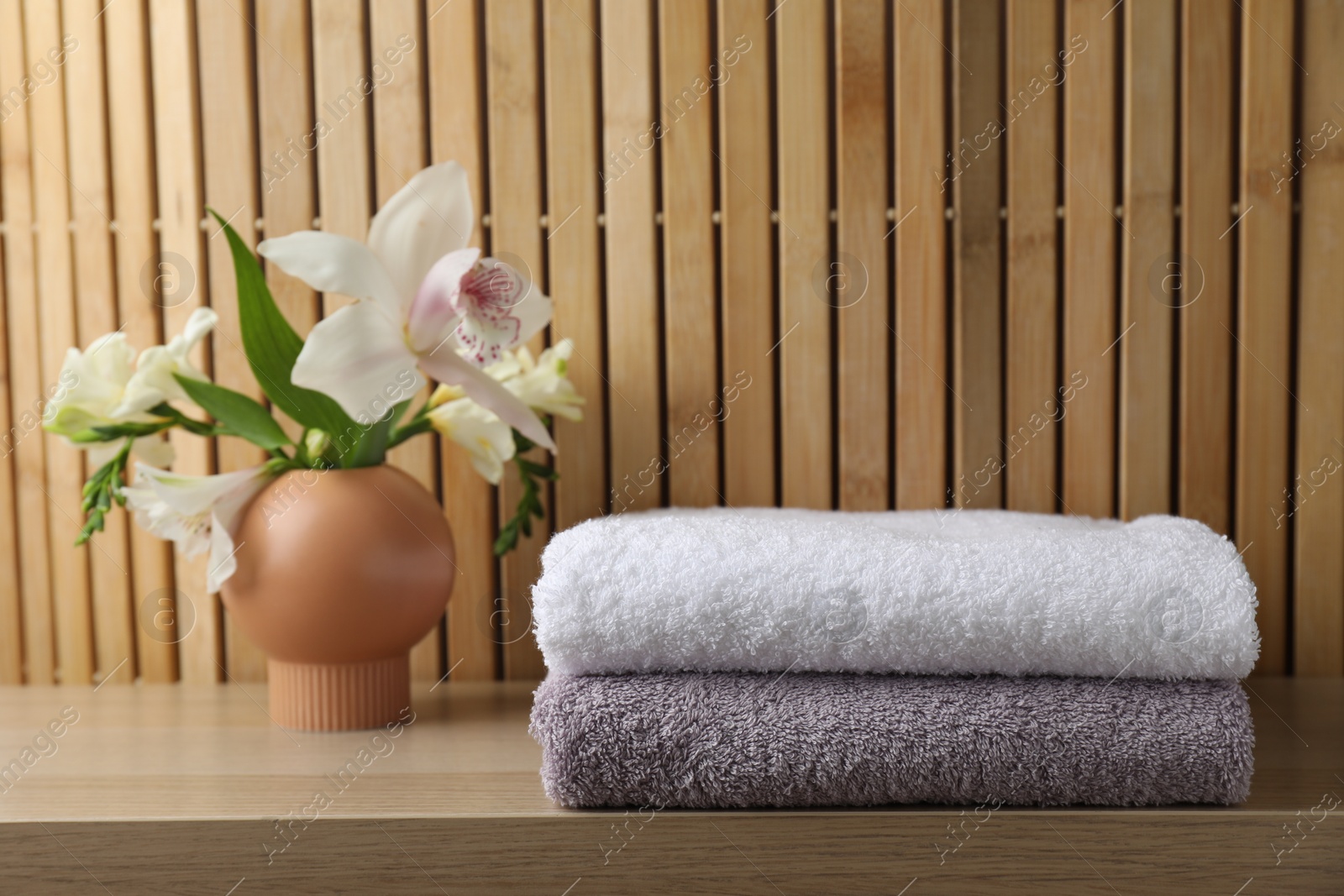 Photo of Terry towels and beautiful flowers on wooden table