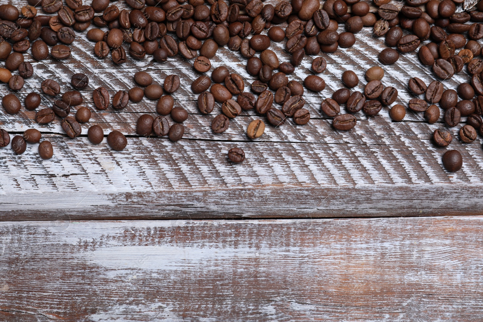 Photo of Many roasted coffee beans on wooden table, flat lay. Space for text