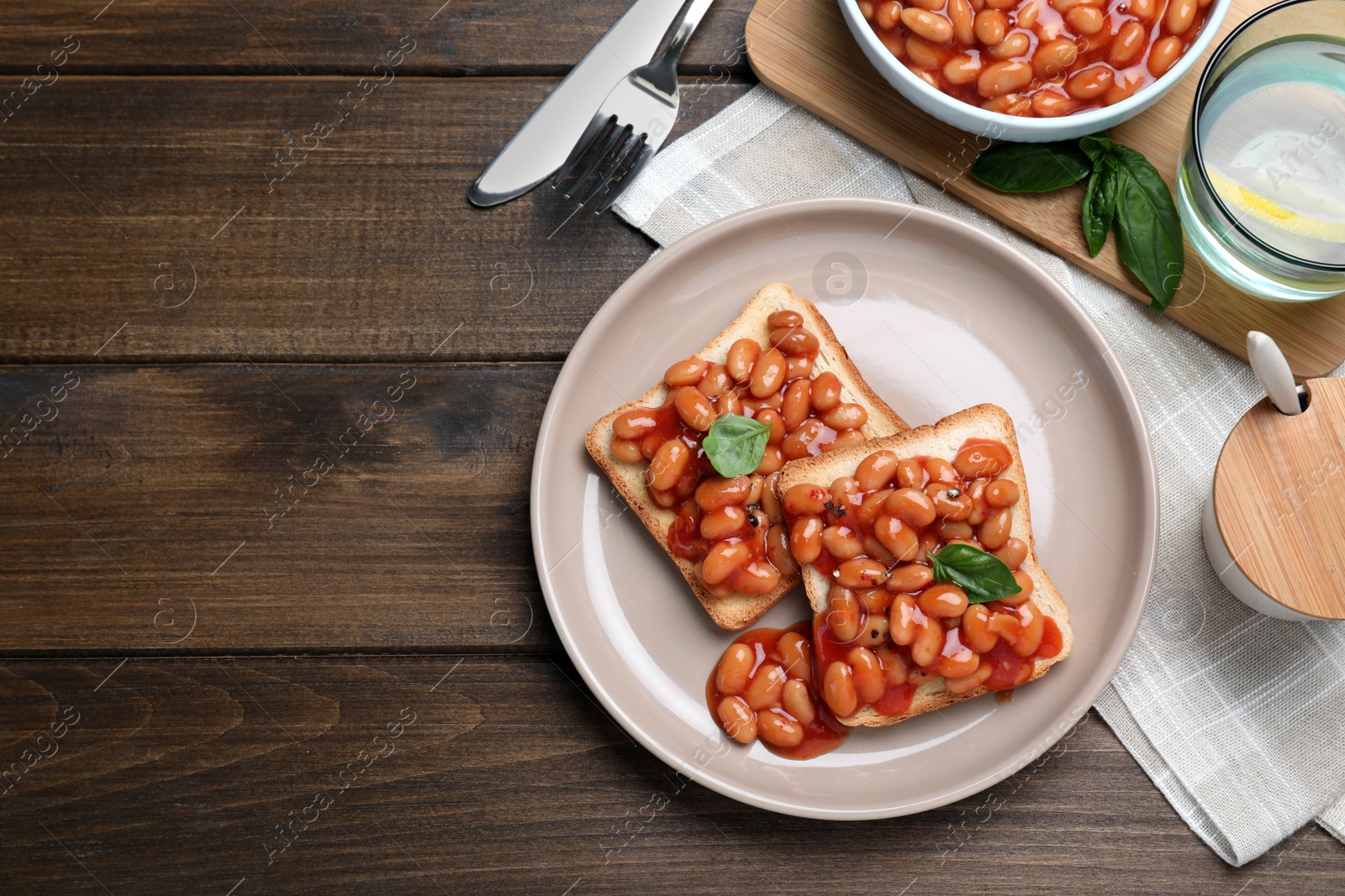 Photo of Toasts with delicious canned beans on wooden table, flat lay. Space for text