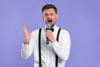 Photo of Handsome man with microphone singing on violet background