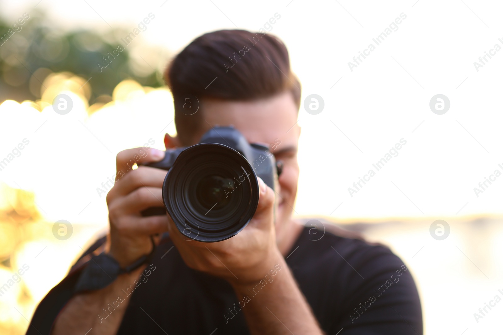 Photo of Photographer taking picture with professional camera in countryside, focus on lens