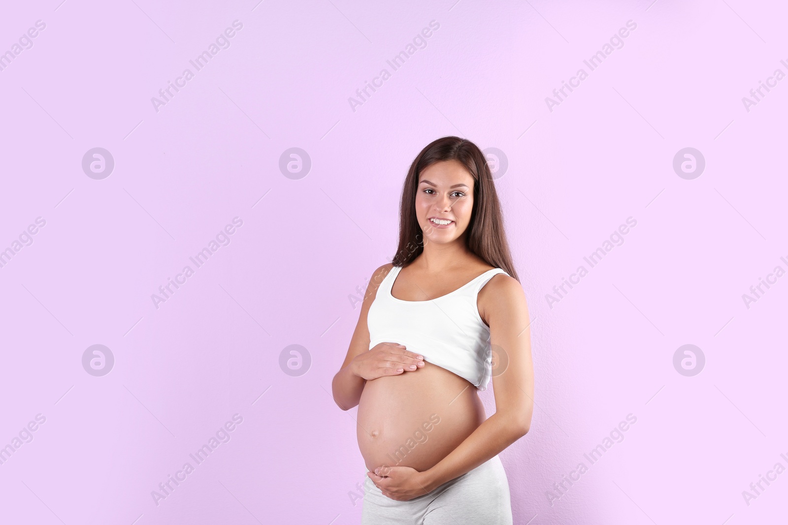 Photo of Happy pregnant woman posing on color background