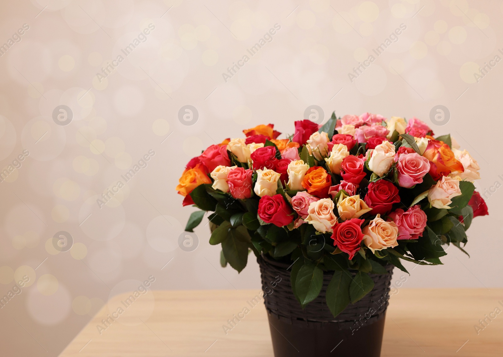 Photo of Bouquet of beautiful roses on wooden table against light background. Space for text