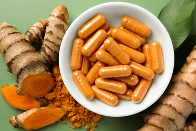 Photo of Aromatic turmeric powder, pills and raw roots on green background, flat lay