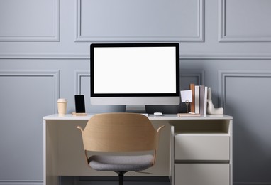 Photo of Cozy workspace with comfortable chair and computer on white desk indoors. Interior design