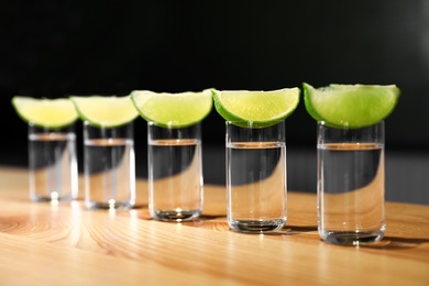 Photo of Vodka shots and lime slices on wooden bar counter