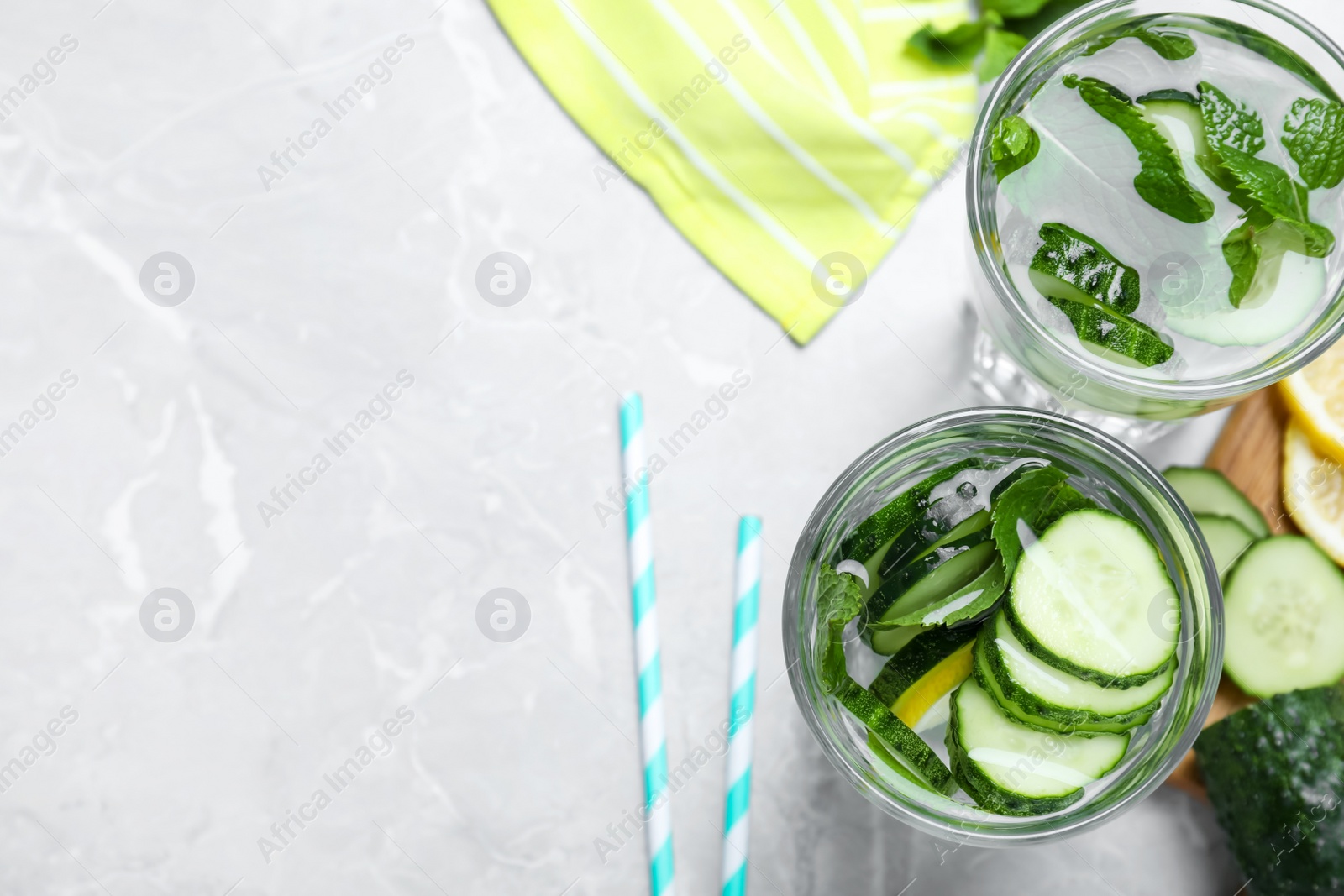 Photo of Refreshing water with cucumber, lemon and mint on light grey table, flat lay. Space for text