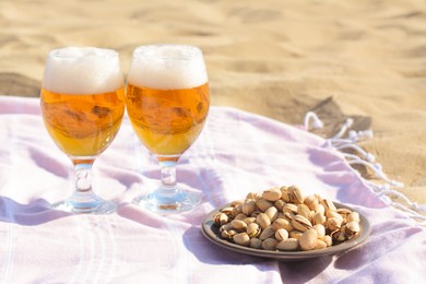Glasses of cold beer and pistachios on sandy beach