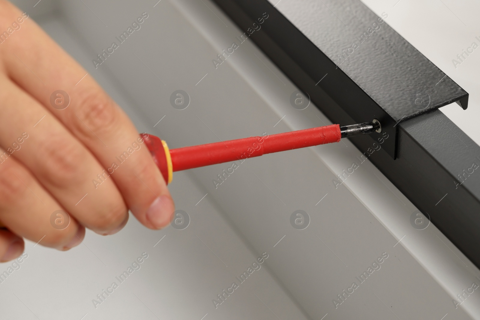 Photo of Woman with screwdriver assembling drawer indoors, closeup