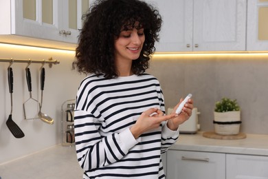 Diabetes. Woman using lancet pen in kitchen