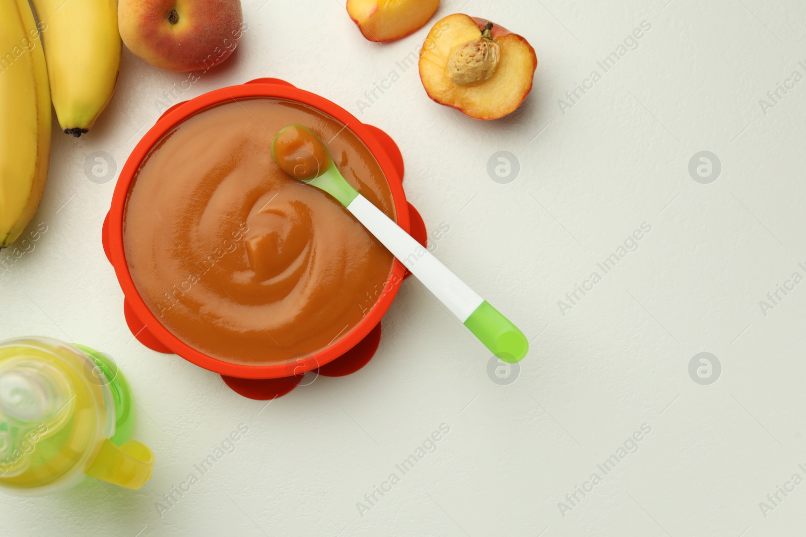 Photo of Tasty pureed baby food and ingredients on white table, flat lay. Space for text