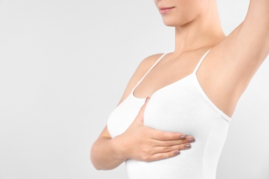 Woman checking her breast on white background, closeup. Space for text