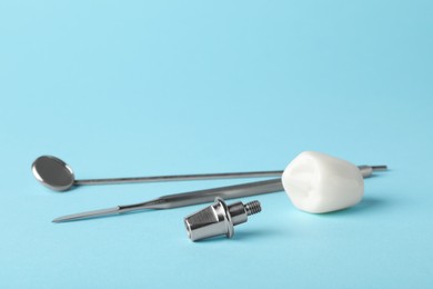 Photo of Abutment and crown of dental implant near medical tools on light blue background. Space for text