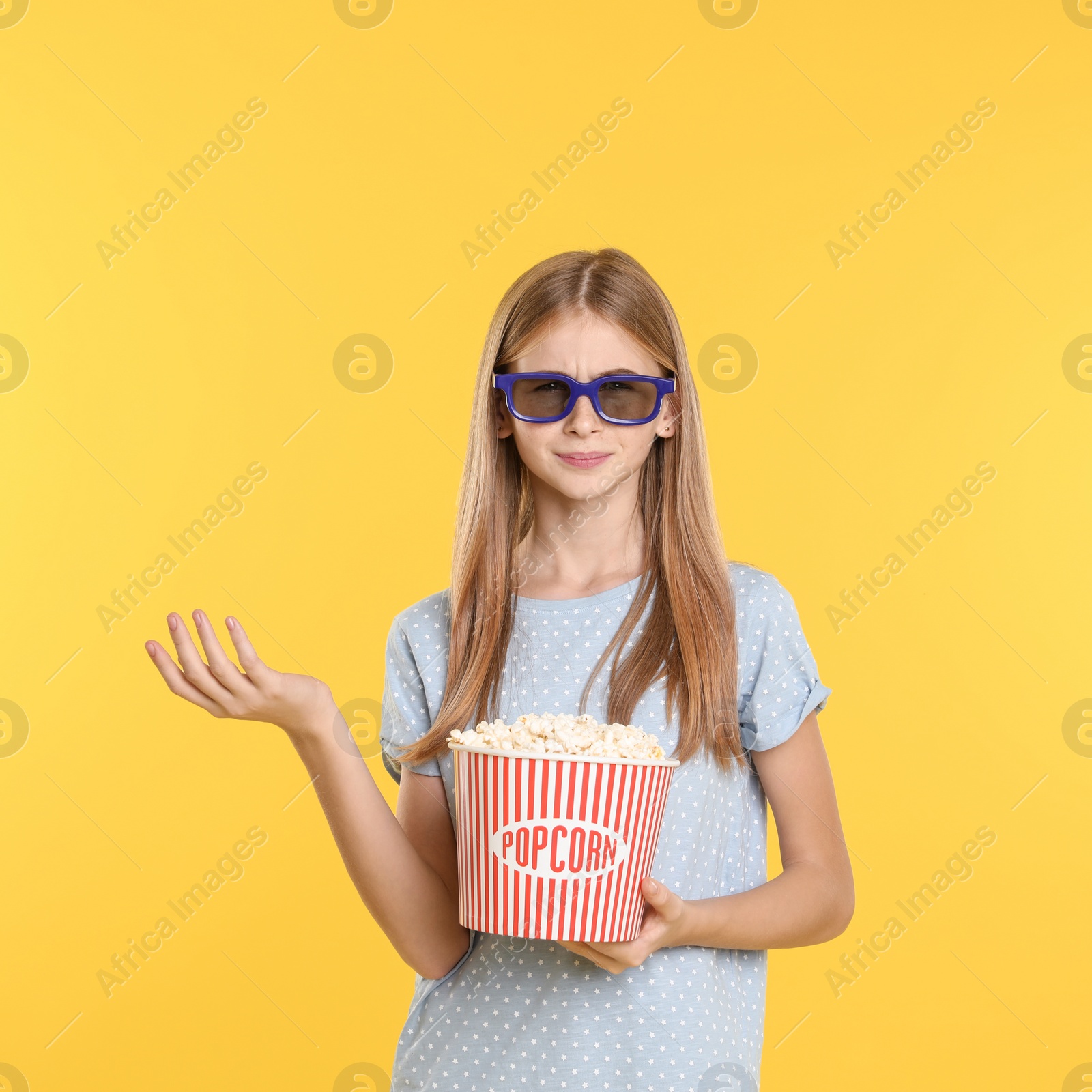Photo of Emotional teenage girl with 3D glasses and popcorn during cinema show on color background