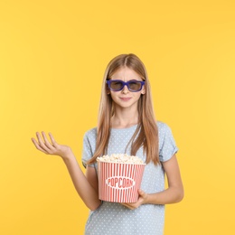 Photo of Emotional teenage girl with 3D glasses and popcorn during cinema show on color background