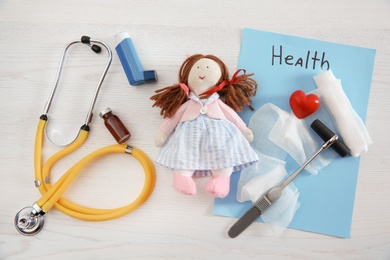 Photo of Flat lay composition with doll and medical items on wooden background. Children's doctor