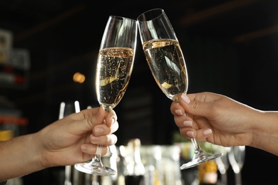Photo of Couple clinking with glasses of champagne in bar, closeup