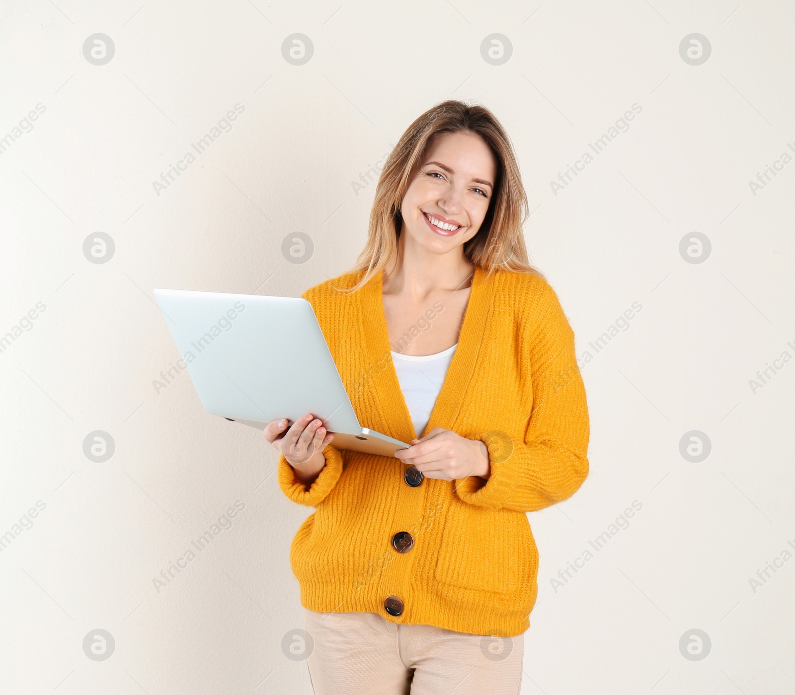 Photo of Portrait of young woman in casual outfit with laptop on light background. Space for text
