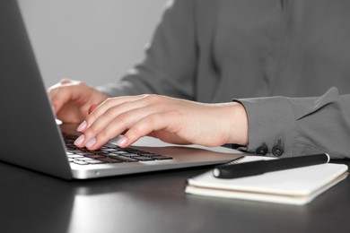 Photo of Woman typing on laptop at table, closeup. Electronic document management