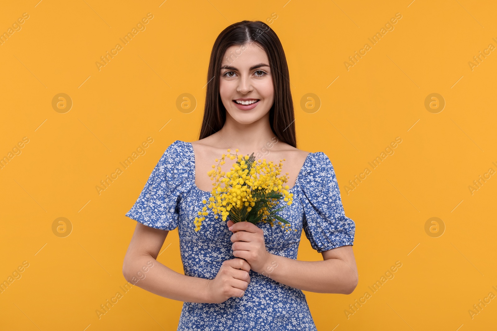 Photo of Happy young woman with beautiful bouquet on orange background