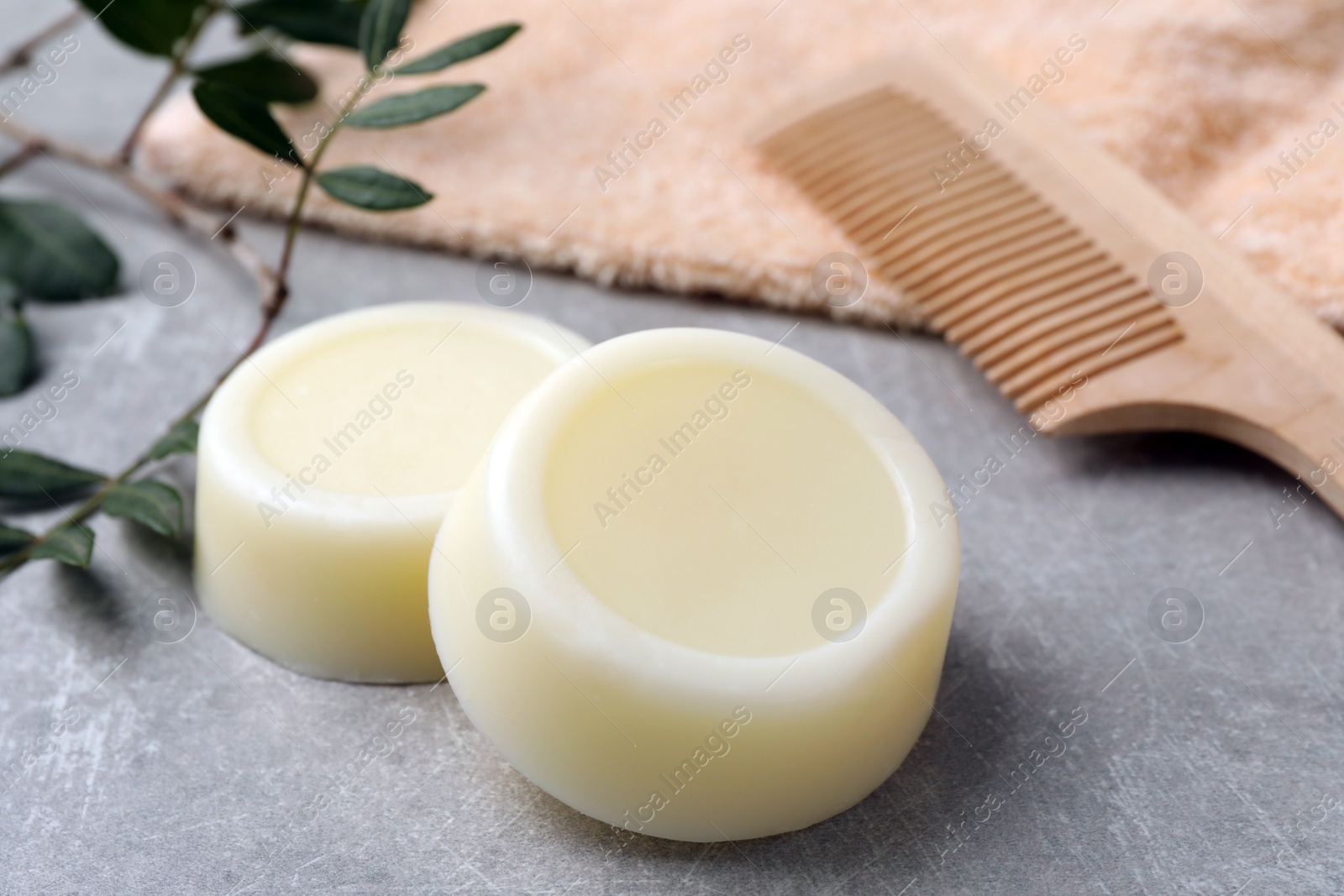 Photo of Solid shampoo bars, green twig and comb on grey table