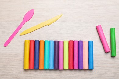Photo of Colorful plasticine and tools on wooden table, flat lay