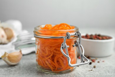 Photo of Delicious Korean carrot salad in glass jar on grey table