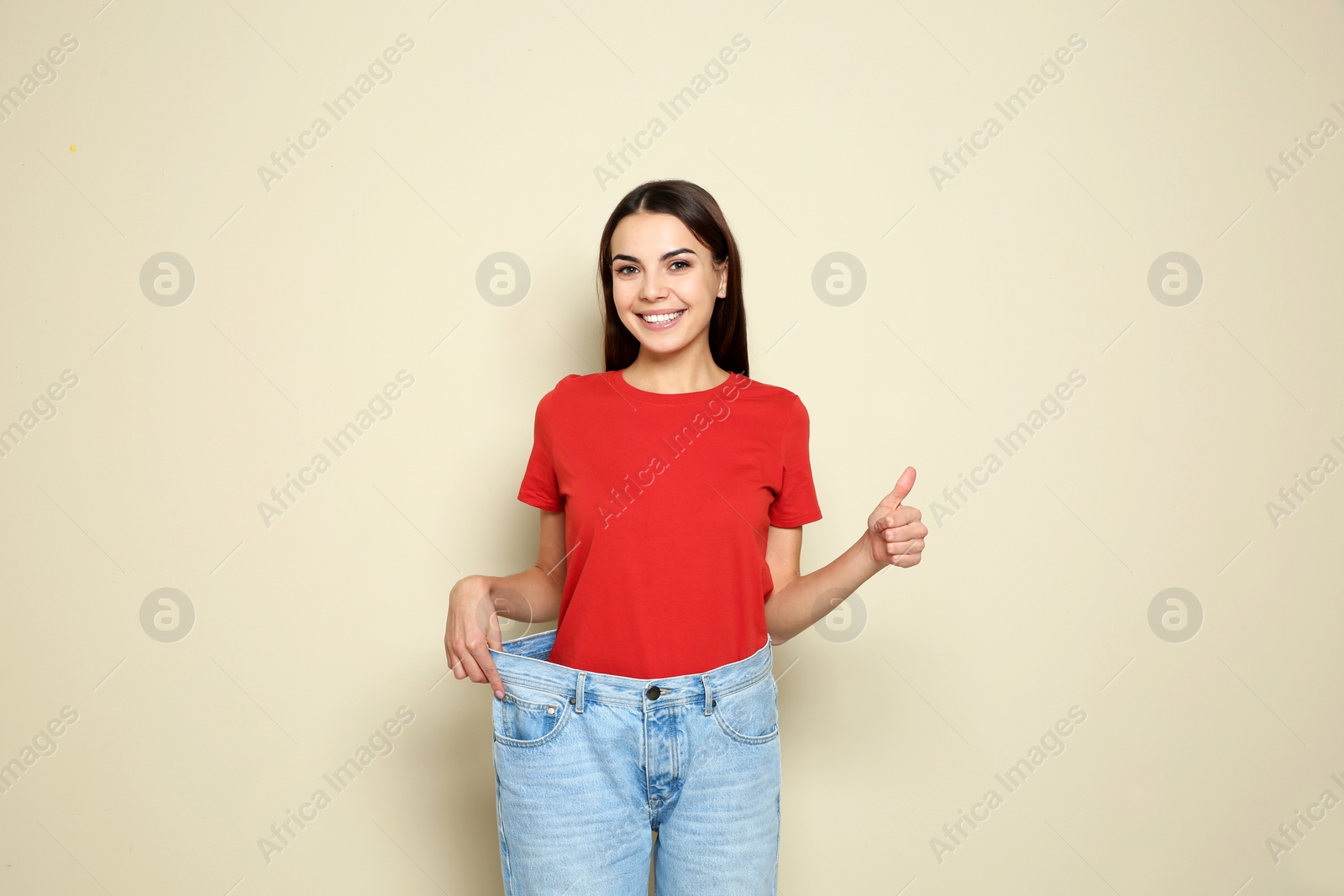 Photo of Slim woman in oversized jeans on color background. Weight loss