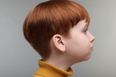 Photo of Hearing problem. Little boy on grey background