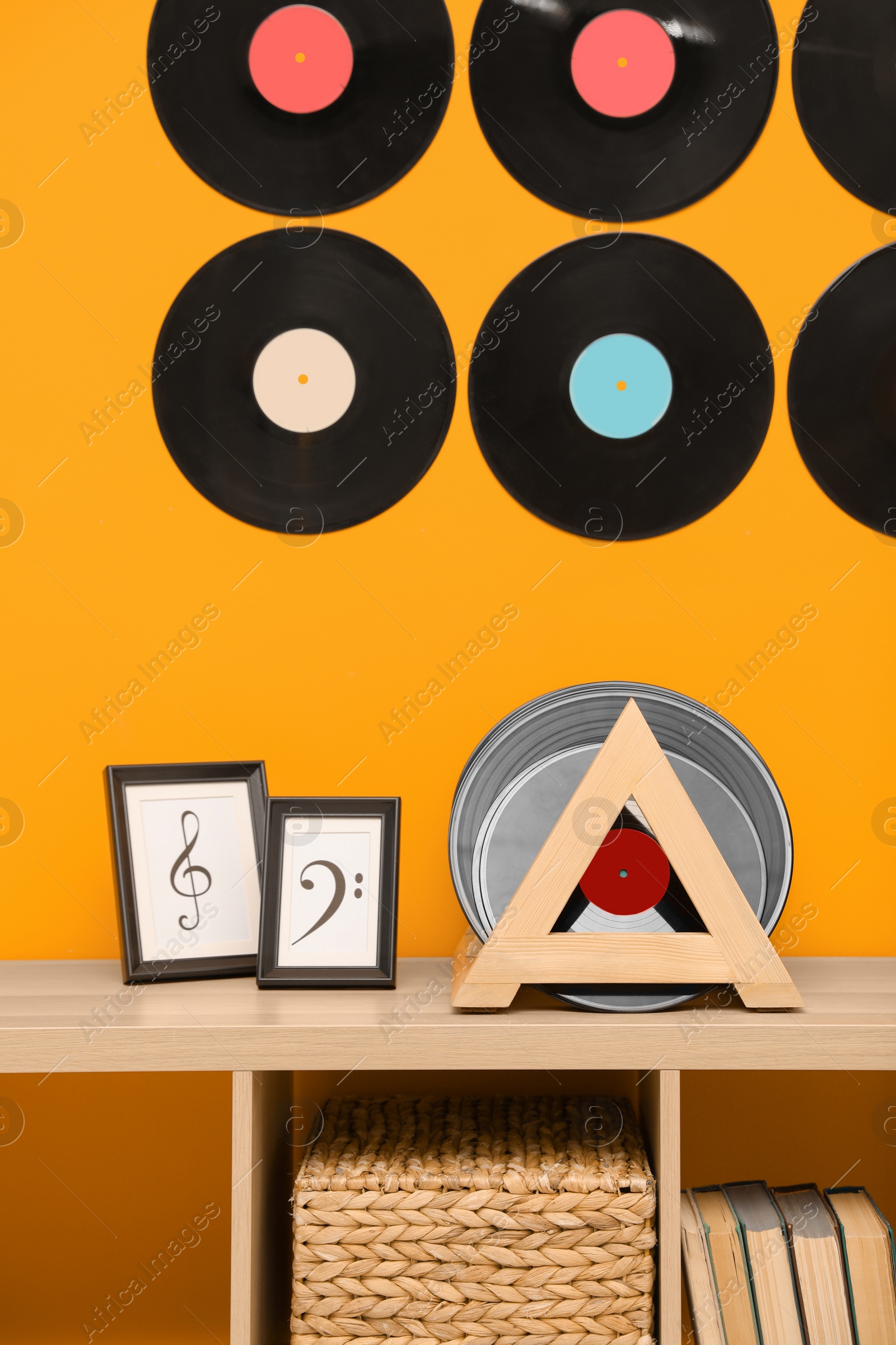 Photo of Vinyl records and pictures on wooden cabinet near orange wall