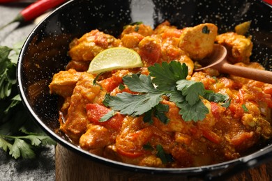 Photo of Delicious chicken curry in frying pan on table, closeup