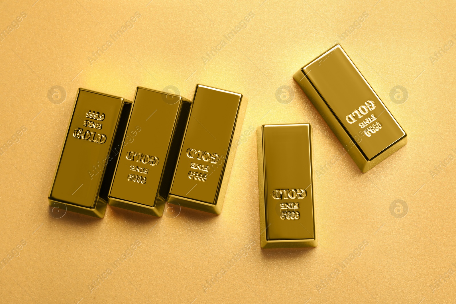 Photo of Shiny gold bars on pale orange background, flat lay